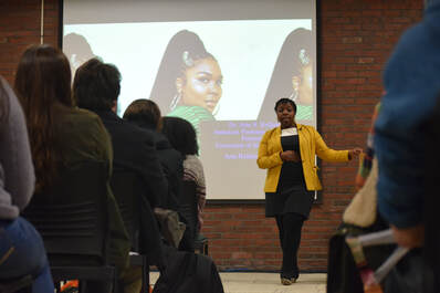 Dr. Halliday giving a lecture to an audience on The Afrofutures of Feminism